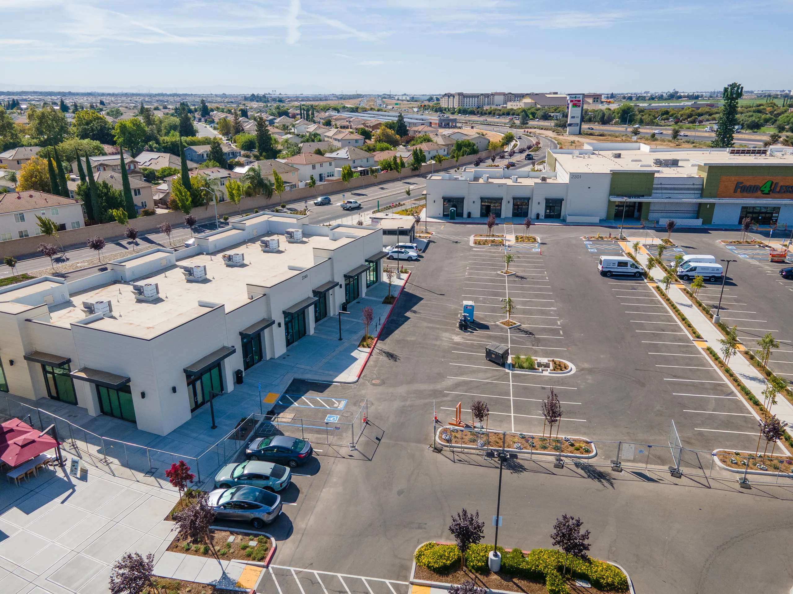 Aerial view of the Shops H building in the foreground with Food 4 Less behind it and Airport Way to the left